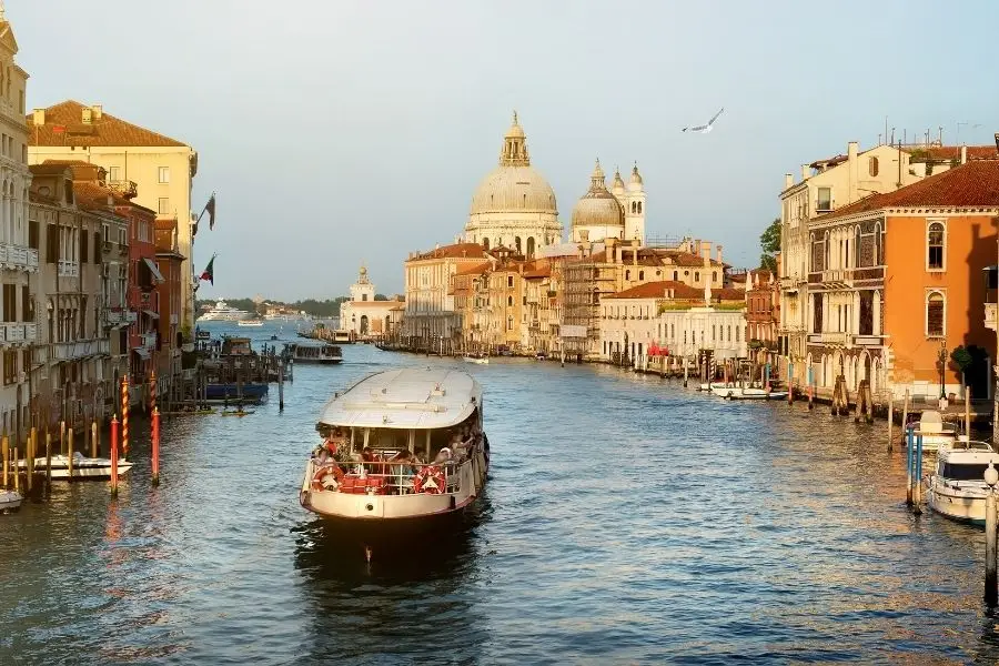 A vaporetto on the Grand Canal at golden hour with the dome of Santa Maria della Salute behind